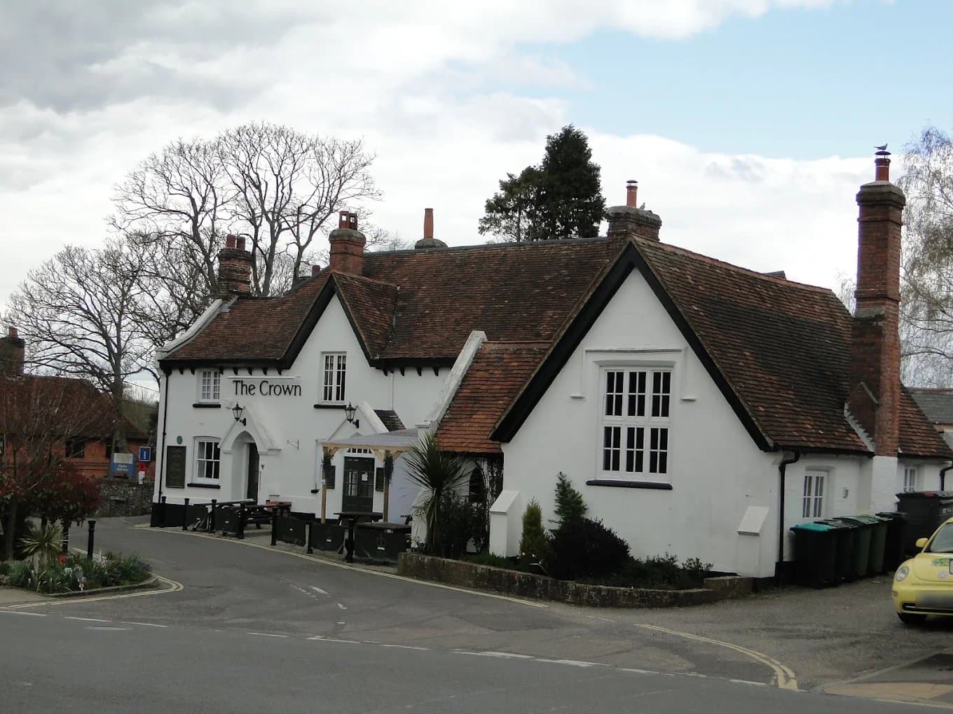 The Crown at Kingsclere, a white painted pub with a dark tiled roof and brick chimneys on a street corner.